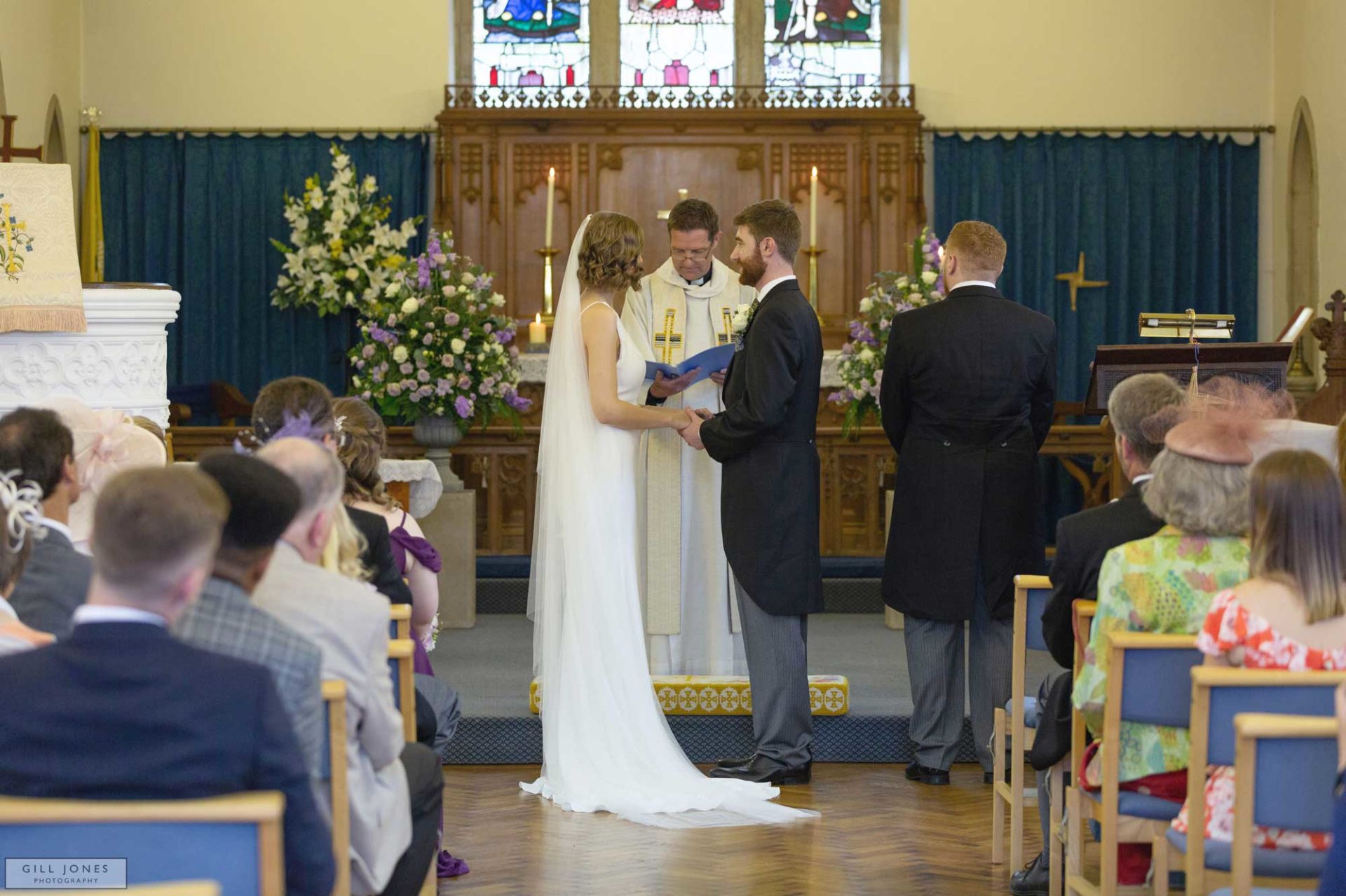the bride and groom are repeating their vows to one another in St. Ffraids church, Trearddur Bay