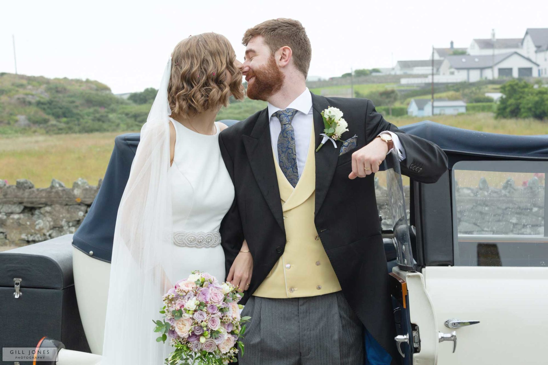 the bride and groom are just about to kiss whilst standing by a vintage wedding car