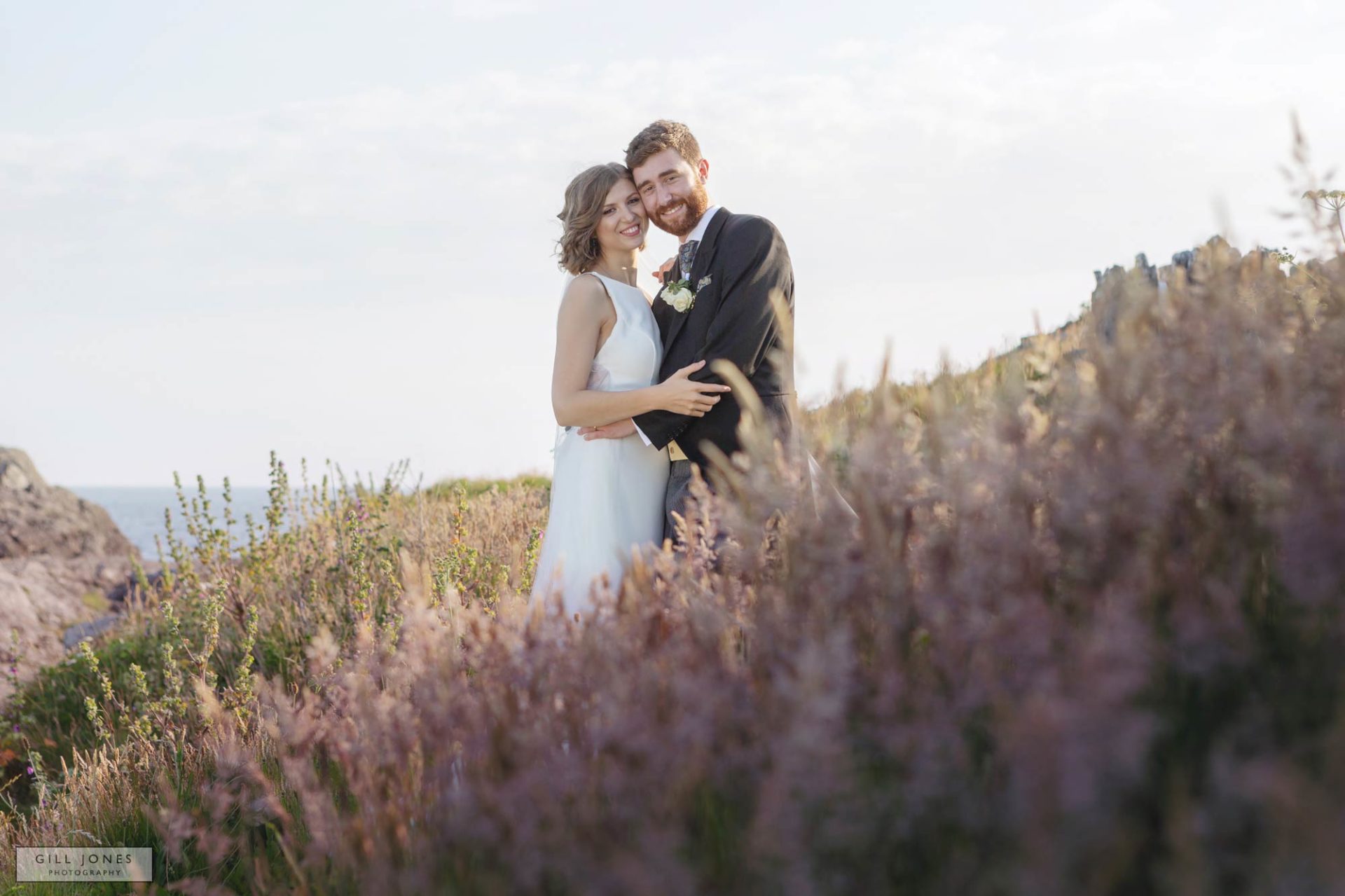 a bride and groom are caressing within pink heather