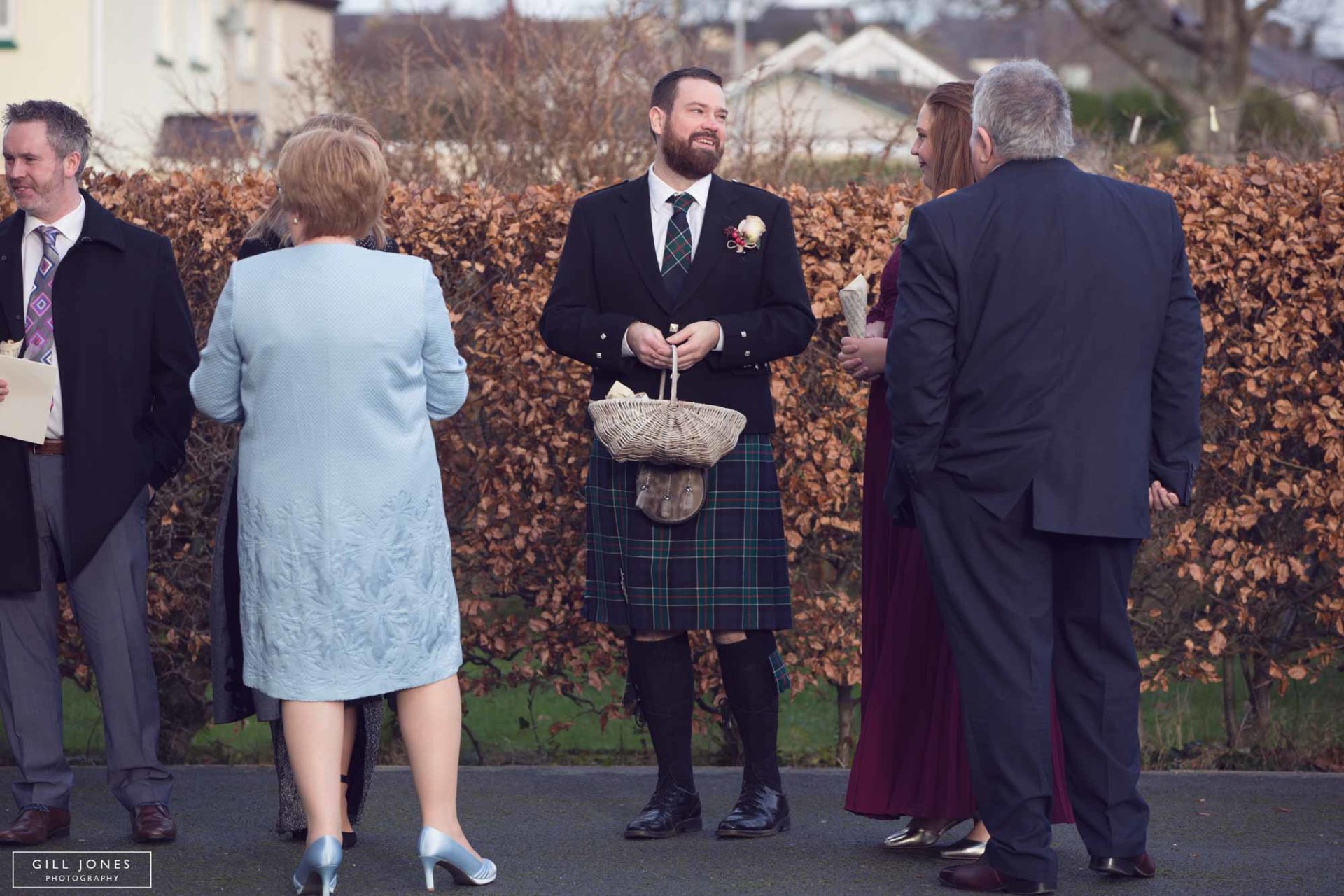 a groomsman holding a basket of flowers