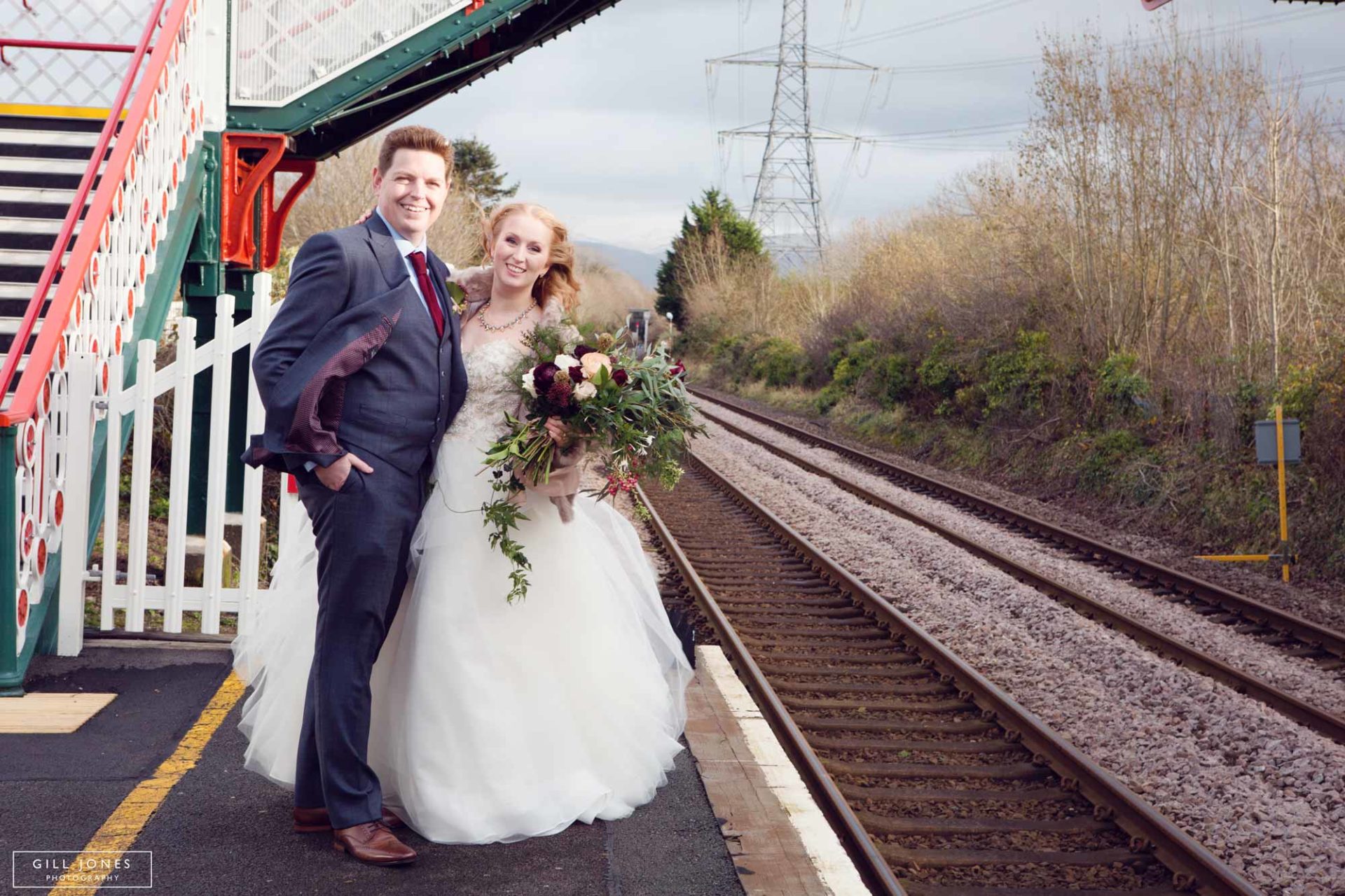 the bride and groom standing close at the rail station