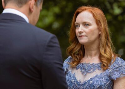 a woman in a blue dress, blue eyes and red hair looks towards her husband by Anglesey elopement photographer Gill Jones Photography