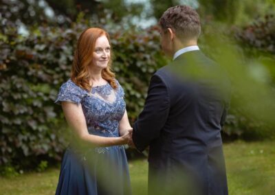 a woman wearing a blue dress holds hands with her husband and looks into his eyes by Anglesey elopement photographer Gill Jones Photography