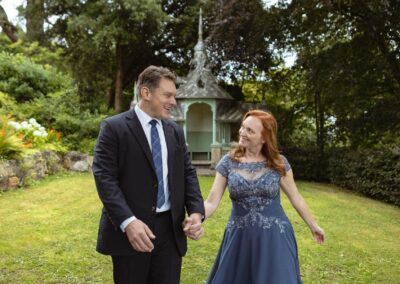 a man and woman walk swinging hands they smile at one another by Anglesey elopement photographer Gill Jones Photography