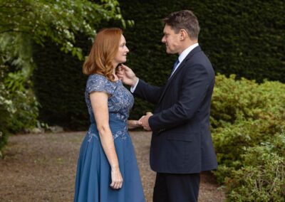 a man holds his wife's hand and he reaches to caress her chin by Anglesey elopement photographer Gill Jones Photography