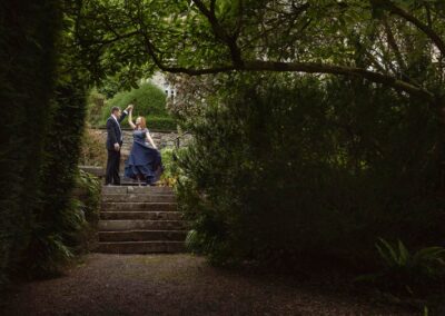 a woman holds her dress whilst she twirls under her husband's arm by Anglesey elopement photographer Gill Jones Photography