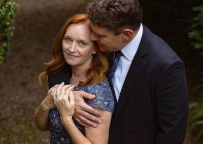 a man holds his wife across her shoulders and whispers in her ear by Anglesey elopement photographer Gill Jones Photography