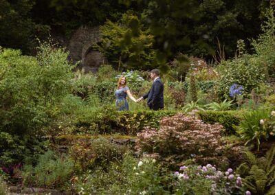 a woman leads her husband through a garden by the hand by Anglesey elopement photographer Gill Jones Photography