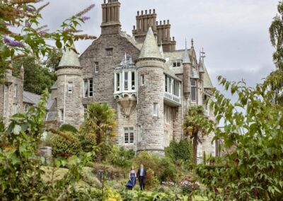 a man and woman stand hand in hand infront of a chateau by Anglesey elopement photographer Gill Jones Photography