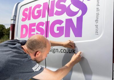 a man applies a sticker to the back door of a van by Anglesey commercial photographer Gill Jones photography