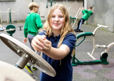 a girl smiles as she plays on a pice of playground apparatus by Anglesey commercial photographer Gill Jones photography