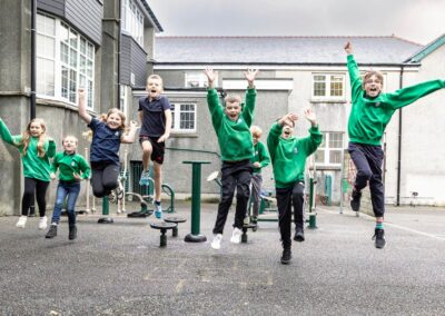 a group of children jump for joy in their playground by Anglesey commercial photographer Gill Jones photography