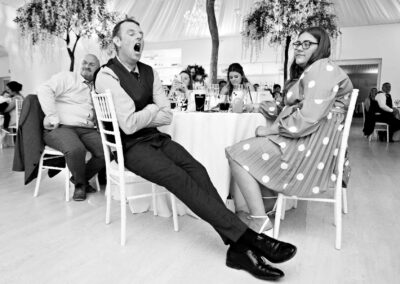 a man yawns widely during wedding speeches as a moan looks on