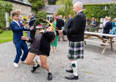 a girl limbos under long grasses held by two wedding guests