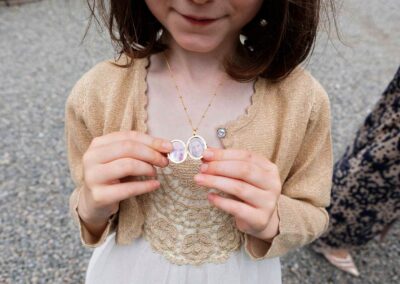 a young girl holds a locket open showing photographs of her mother and father