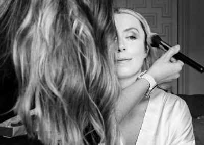 a bride sits whilst a make up artist applies powder to her face using a brush