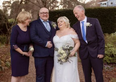 four people stand side by side laughing in an early spring garden