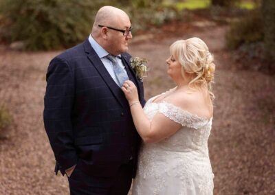 a bride adjusts her husband's tie tenderly as he chats to her