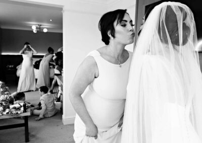 a bridesmaid puckers up and leans to kiss her sister the bride