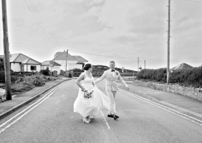 a bride and groom walk across an empty road