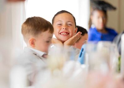 a young boy holds his head between his hands an smiles broadly