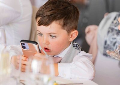 a young boy stares in astonishment at the screen of a mobile phone