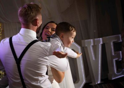 a young boy is held by his parents he stretches his out as if he's flying