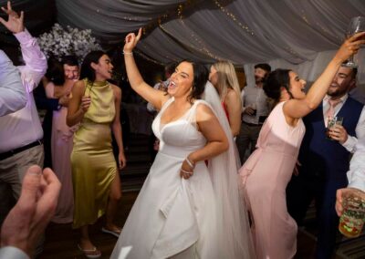 a bride dances enthusiastically surrounded by her guests