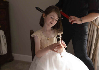 a young girl play with her dill whilst a hairdresser combs her hair