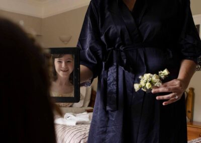 a young girl looks at her reflection, her mother holds a pretty hair slide