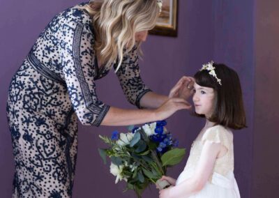 a mother attends to her daughter's hair, the daughter is holding a bouquet