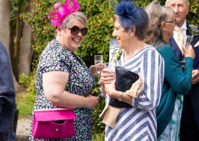 two women wearing bright hats smile broadly whilst having a chat