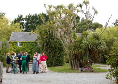 a group of wedding guests stand together within a leafy courtyard surrounded by palm trees