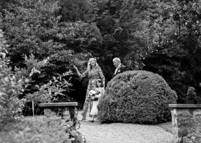 a woman walks with her father and daughter on the way to her wedding ceremony she gestures with her hand that it is not yet raining