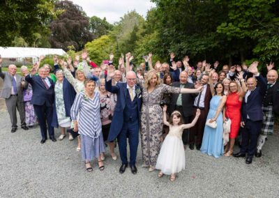 a group of wedding guests look up and cheer for their bride and groom