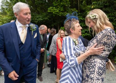 the bride's mother hugs her daughter and smiles whilst her husband looks on