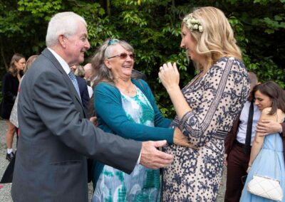 two guests reach to hug a bride