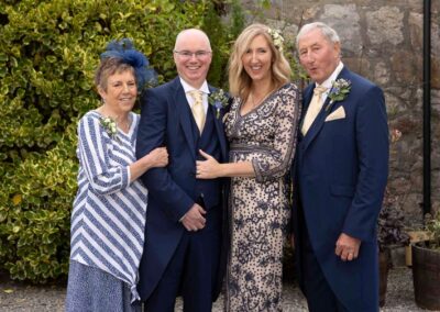 a bride and groom with her parents stand together to face the camera for a typical group shot