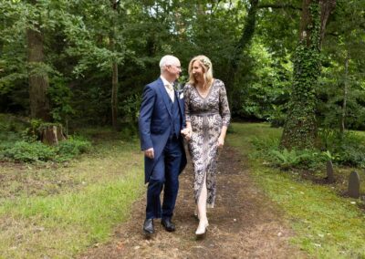 a bride and groom walk briskly hand in hand through a small wooded area