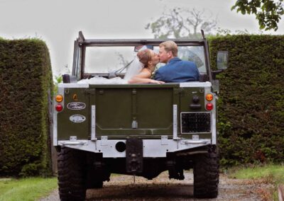 couple kiss as they sit in a soft top Landrover